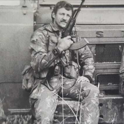Mike West with rifle, vehicle background